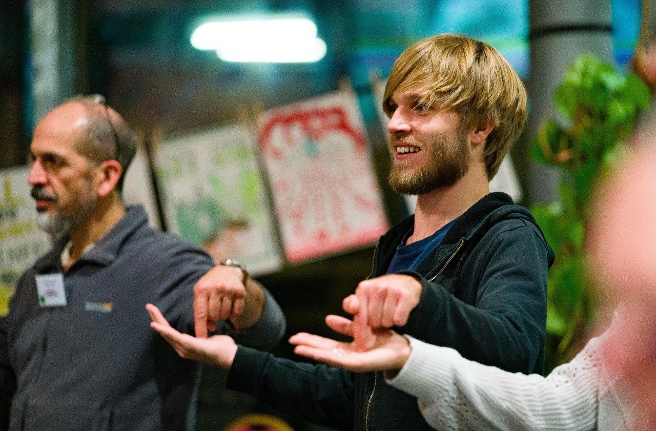 Two men taking part in an ice-breaker activity. They're smiling and holding out their hands.