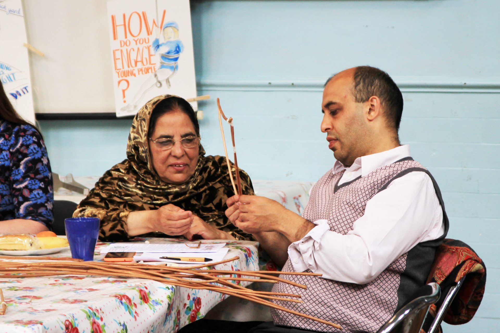 Two people are chatting and doing a craft activity together.