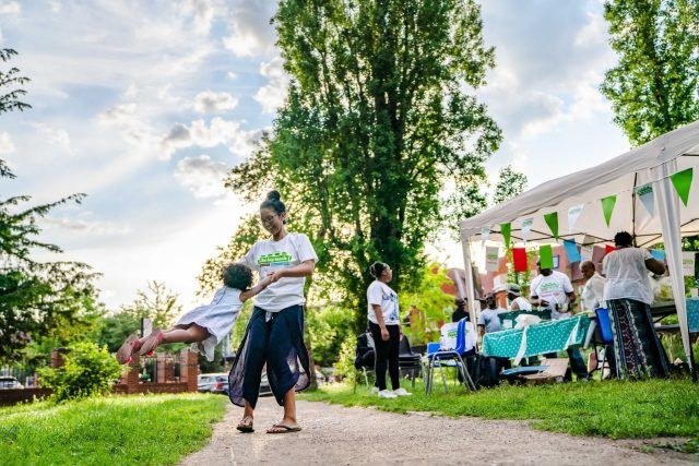 A woman playfully swinging a child in the air at The Big Lunch