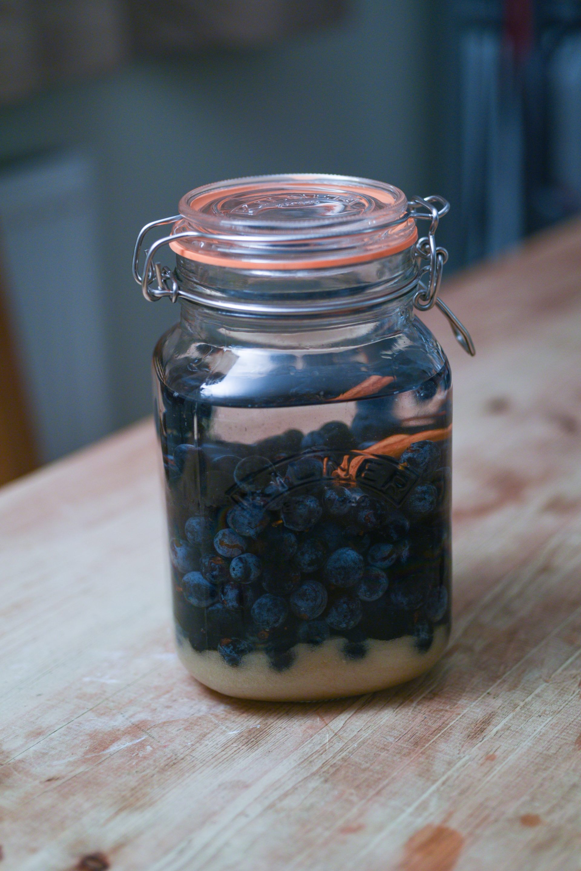 Sloe berries in a jam jar with gin poured over the top and sugar settled at the bottom