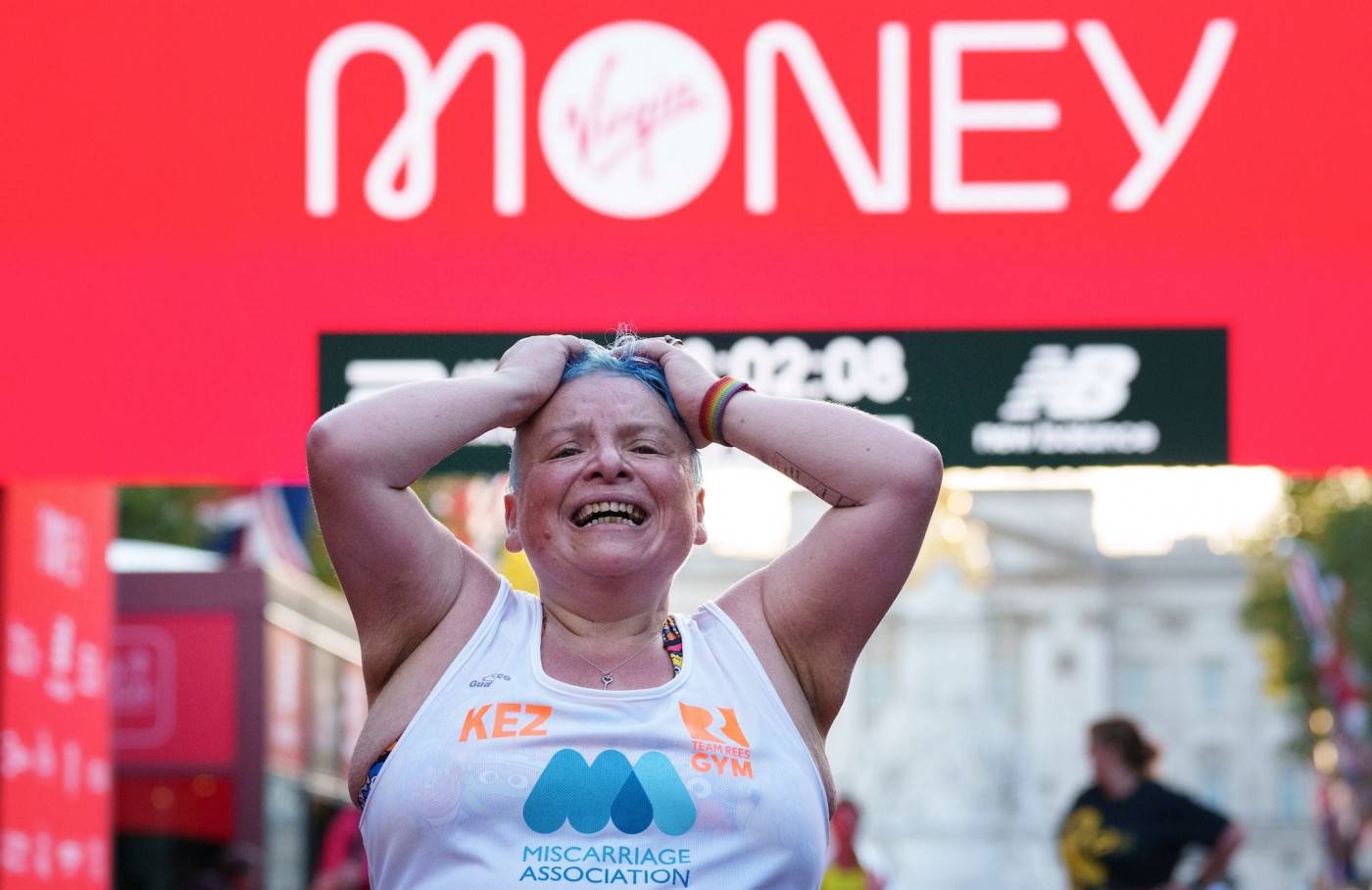 Kerri Aldridge completing the London Marathon. She looks exhausted and elated underneath a finishing banner.