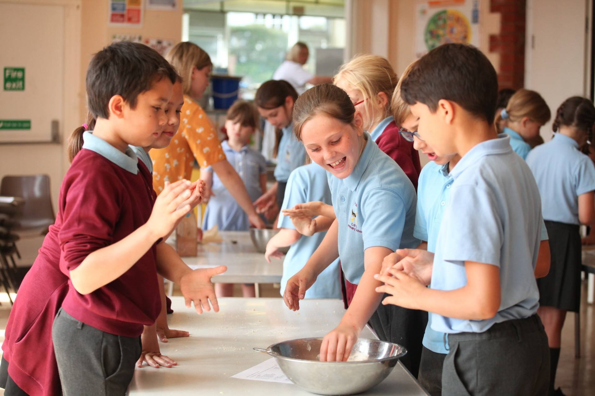 Schoolchildren in uniform stood around metal bowls