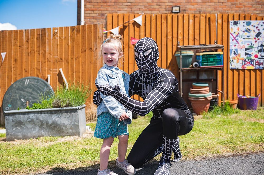 A person dressed as spiderman with a child