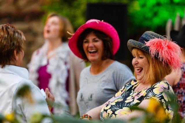 Women trying on elaborate bright and feathered hats