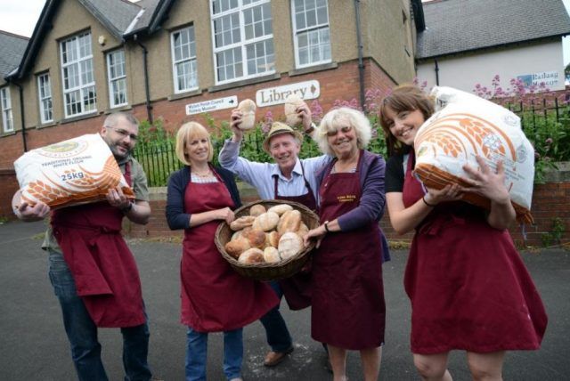 People holding loaves of bread outside library