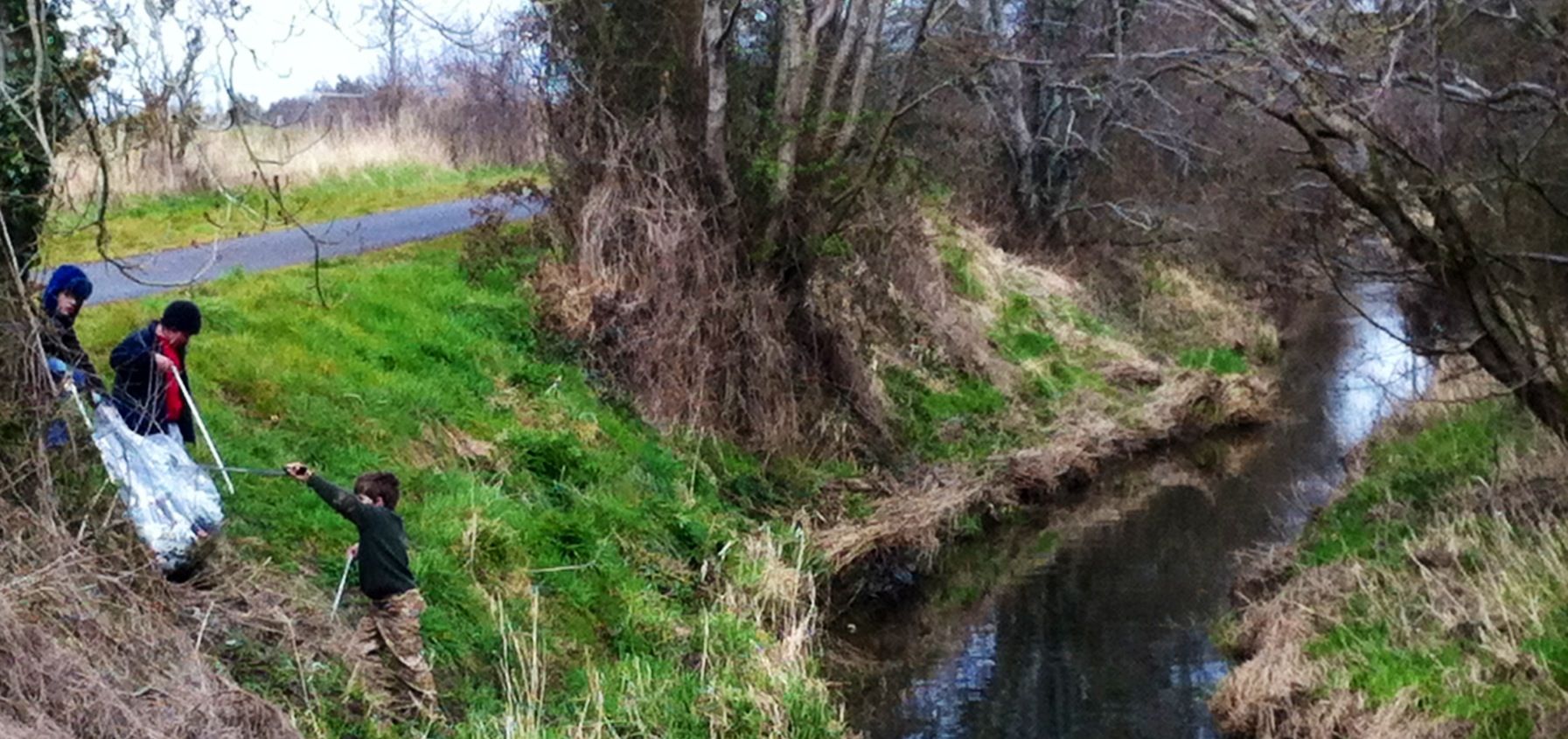 Children picking up rubbish along a creek. 