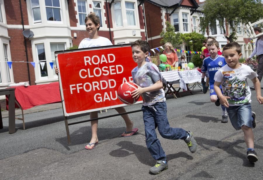 Boys running with a football, boy carrying road closed ahead sign