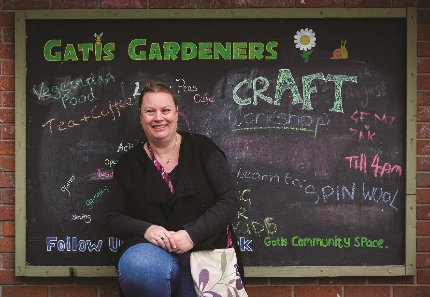 Woman standing in front of chalkboard titled 'Gatis Gardeners'