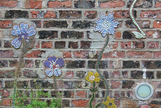 Blue and yellow flower mosaics on brick wall