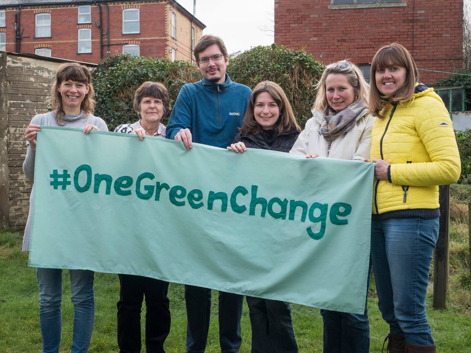 People holding up banner with text saying hashtag one green change