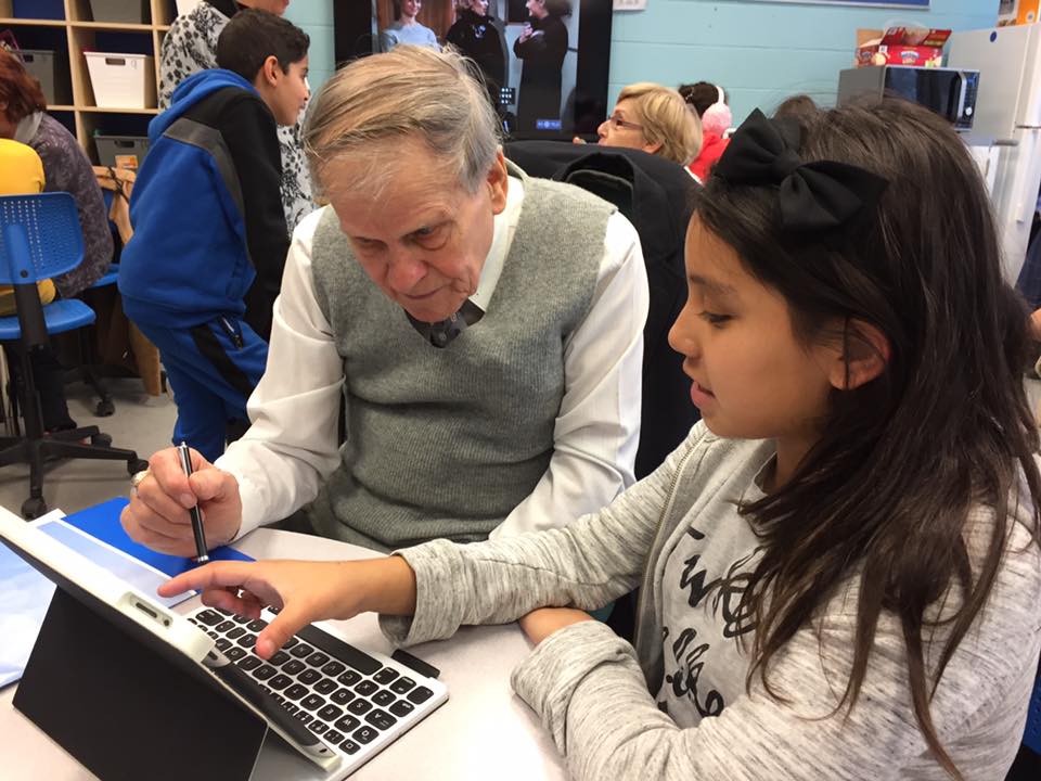 Girl teaching elderly man how to use an ipad