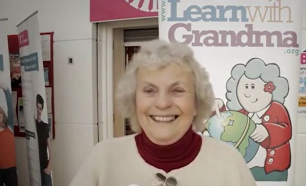 Grandma smiling in front of 'Learn with Grandma' banner