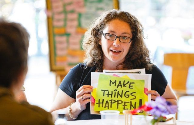 Woman holding 'make things happen sign'