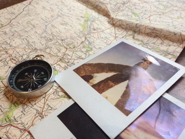 close up of a map with polaroids and a compass placed on top