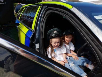 Two children sitting on front seat in a police car
