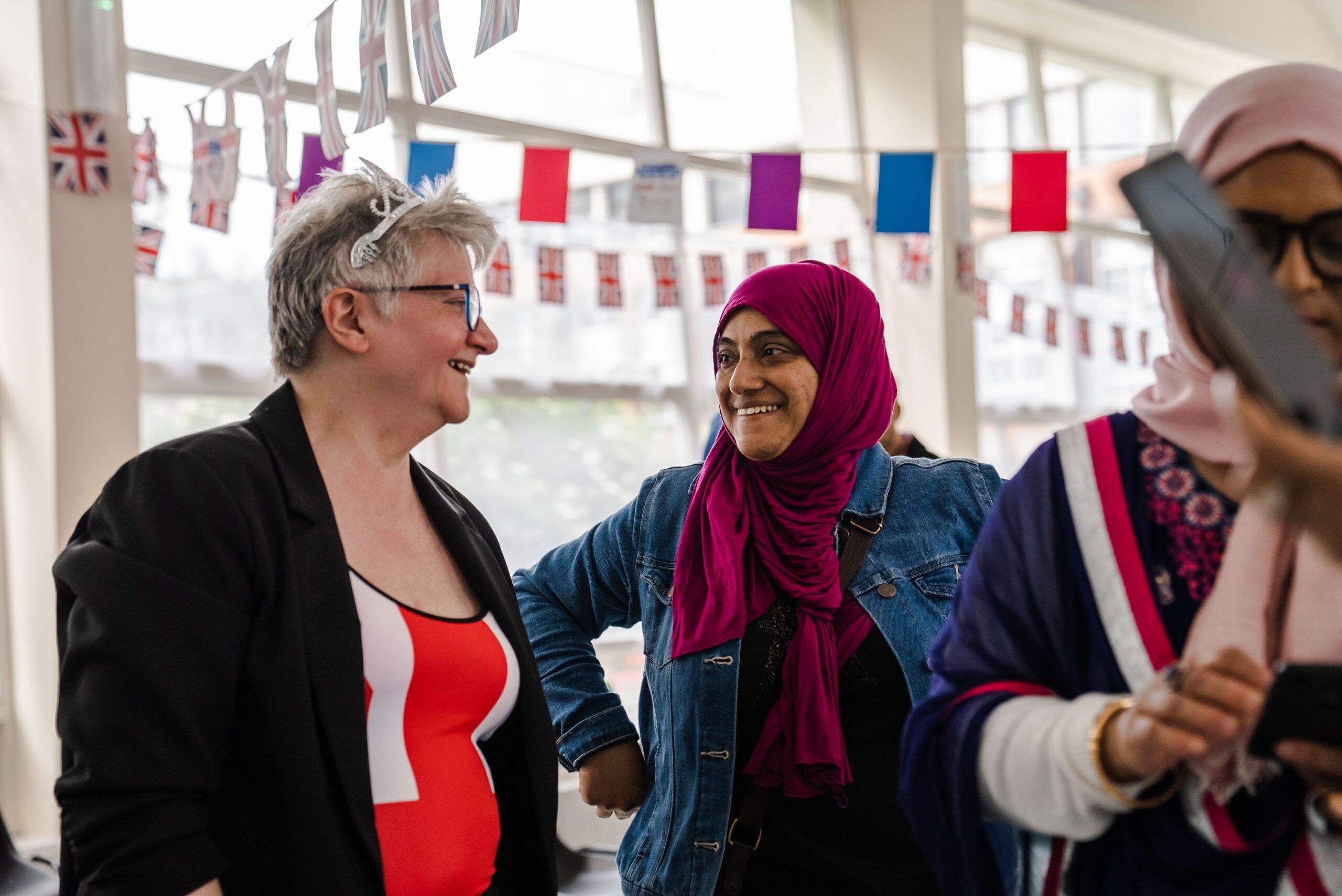 Two ladies smiling and enjoying a conversation at an indoor event with bunting.
