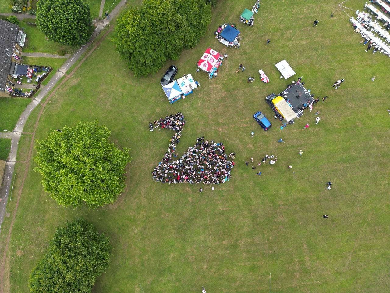 Group of people arranged together so the photo from above shows a swan.