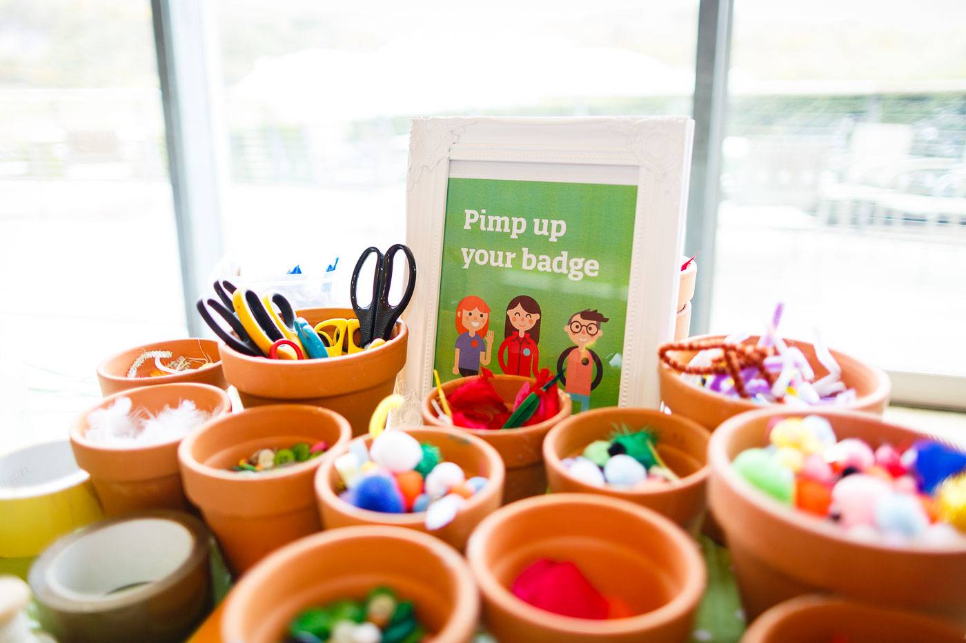 Small terracotta pots with craft supplies such as pompoms and scissors