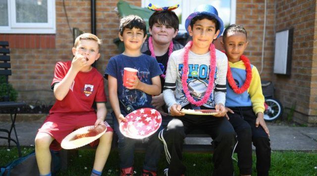 group of children sitting outside with party food