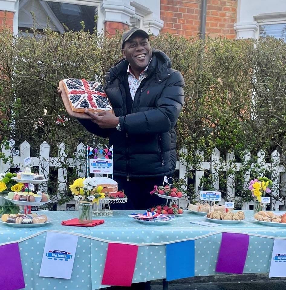 Ainsley Harriott holding a cake decorated with frozen fruit in a Union Jack pattern.