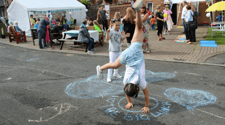 Child doing handstands on chalk art on pavement.