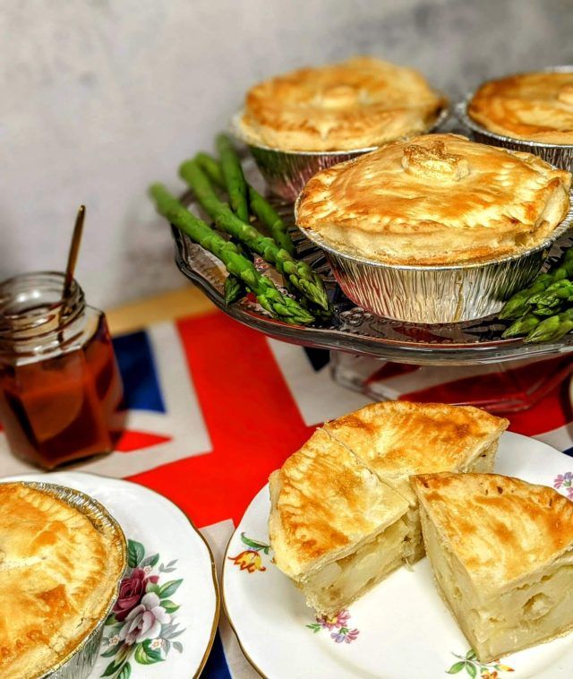 Coronation party pies on plate with asparagus. One is cut open to show a butter and cheese mixture inside.