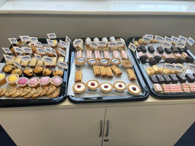 Trays of cakes and buns with 'The Big Lunch' food flags