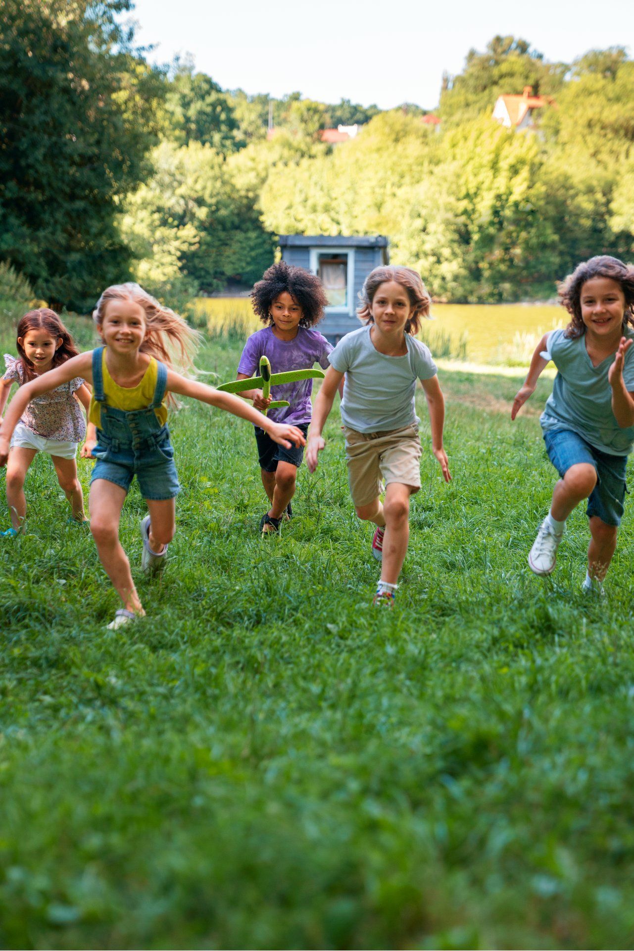 Kids smiling and running towards camera in a grassy area