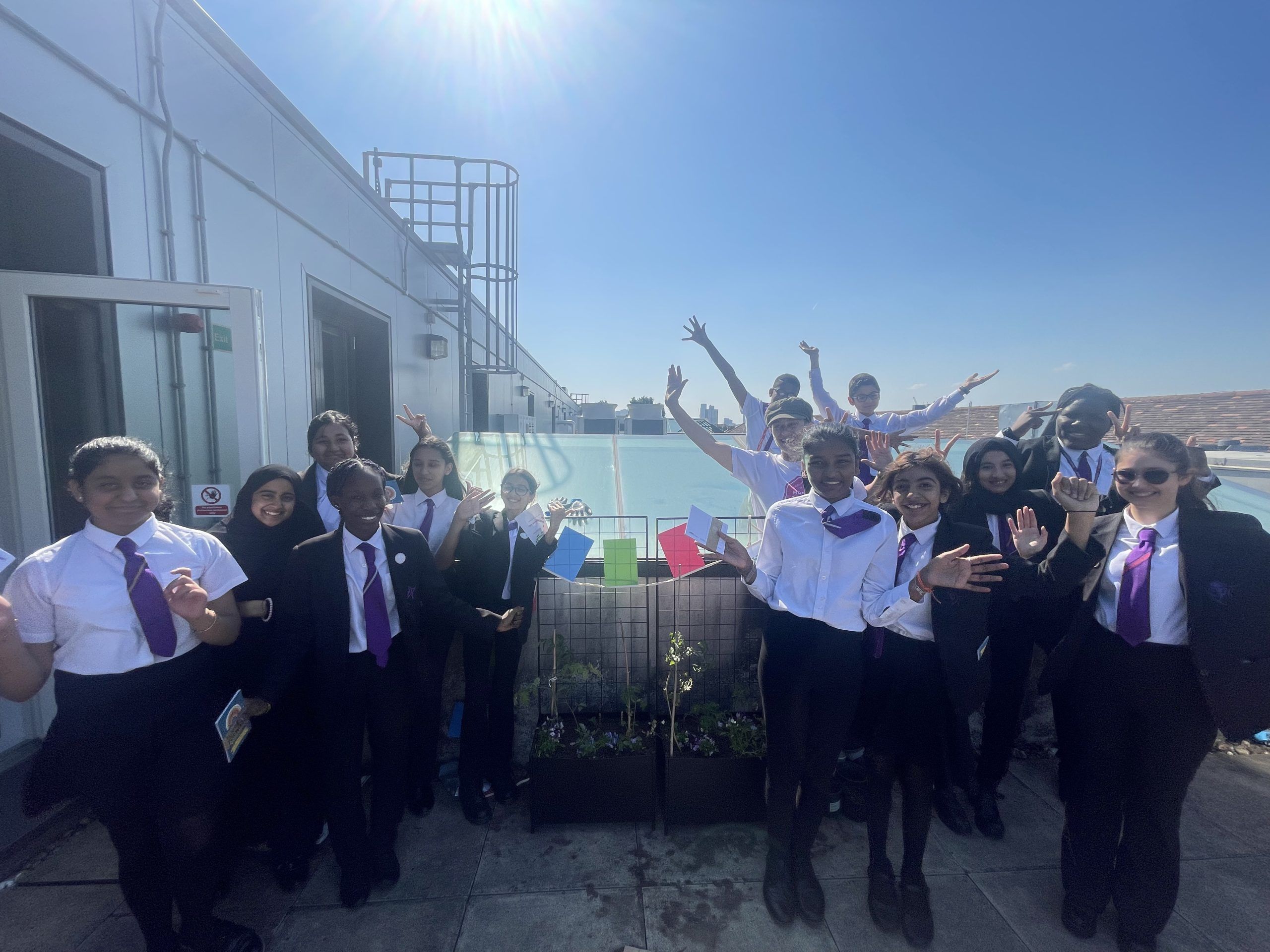 Group of school pupils around a vegetable planter with the produce they're growing. They look really pleased with their efforts!