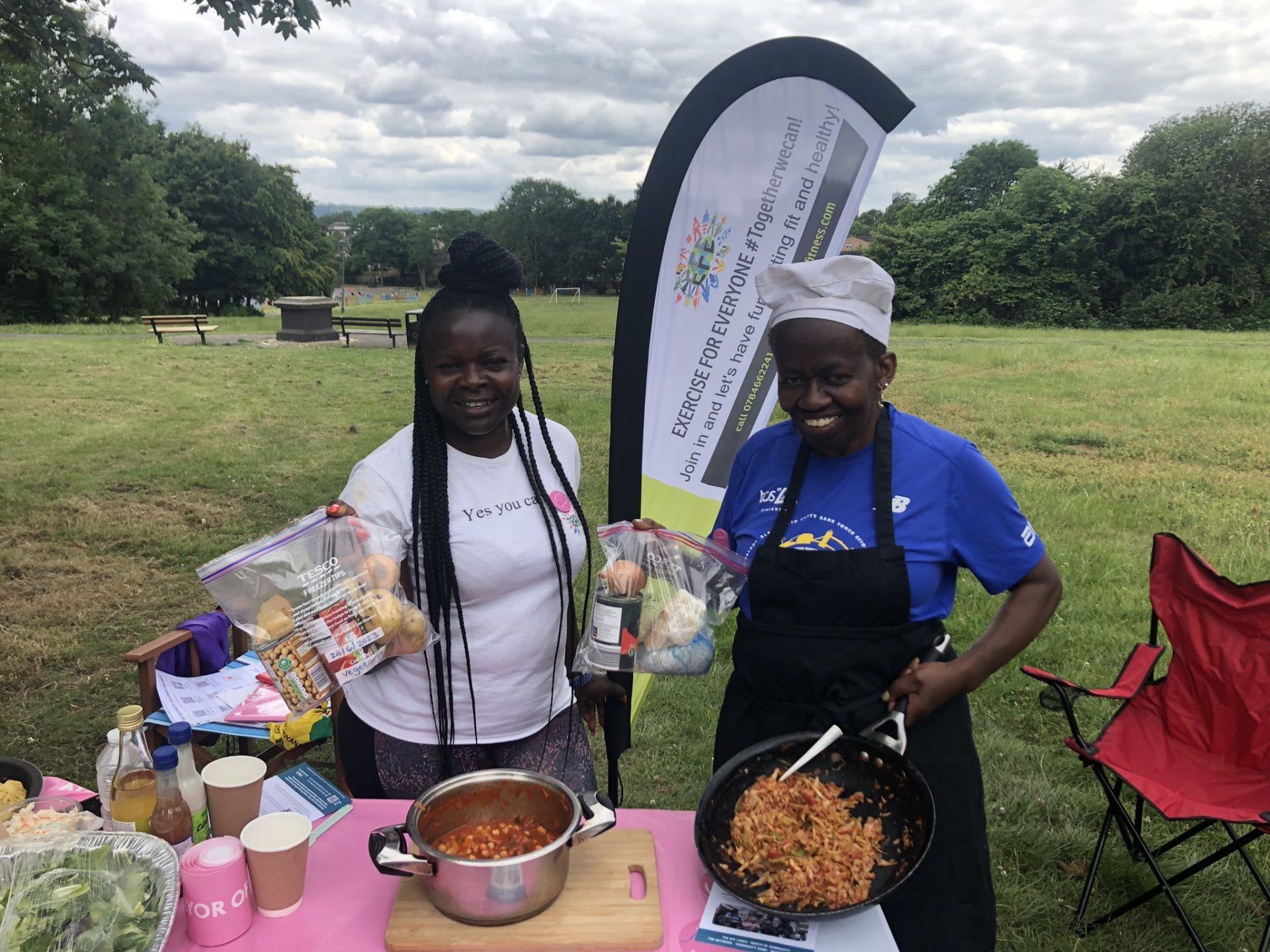 Clarice and Audrey with their pans of delicious-looking food at an outdoor event