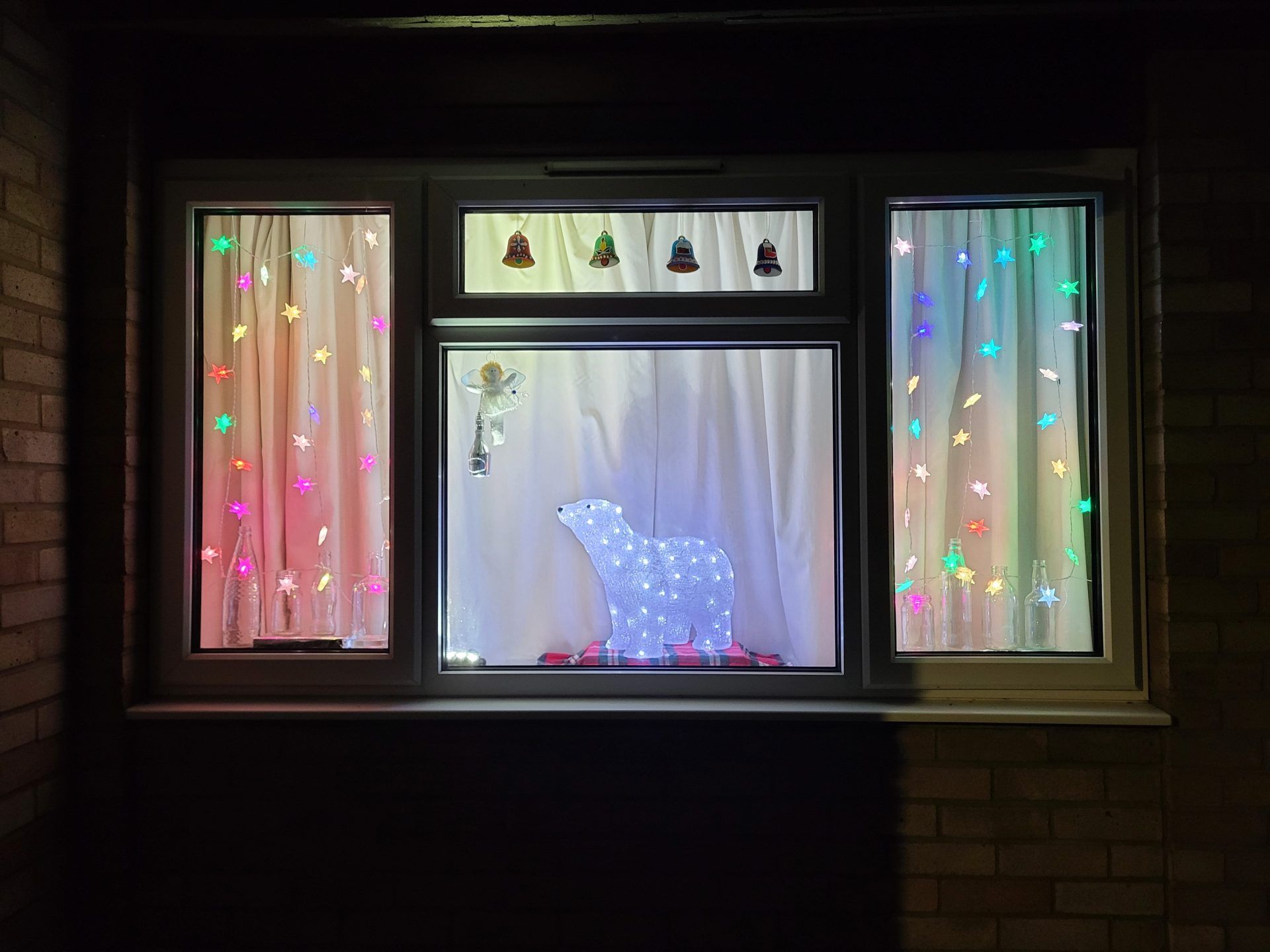 An advent window showing a polar bear amongst colourful fairy lights.