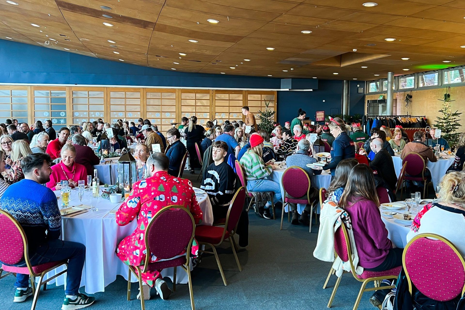 A group of employees having a festive lunch together. They're mostly wearing festive garb