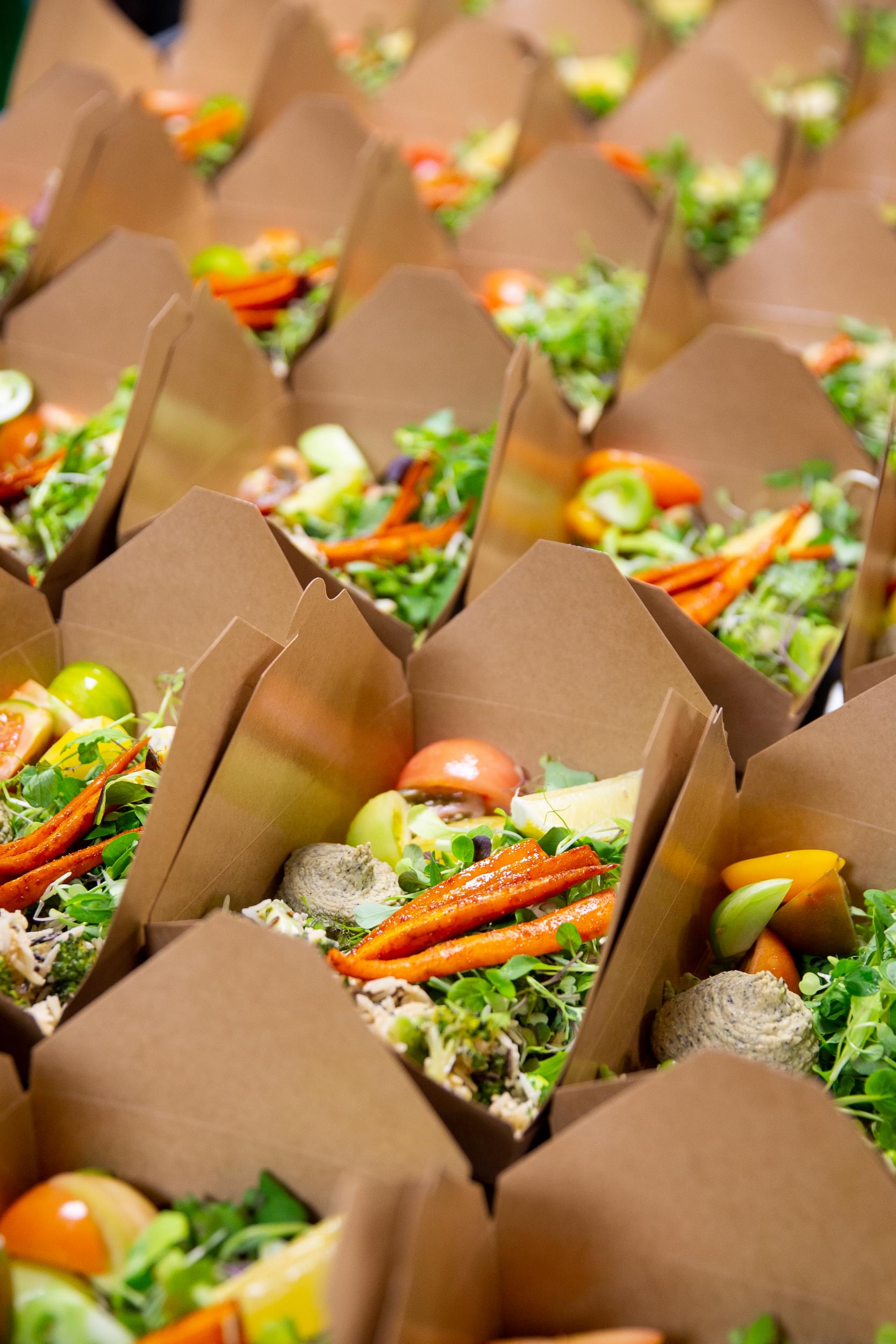 A number of cardboard takeaway containers with a delicious, colourful medley of vegetables and rice inside