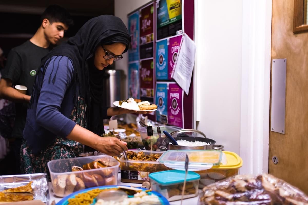 A woman helps herself to a plate of delicious food from a spread of homemade bakes