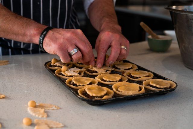Mince pies being prepared - the pastry lid is being placed on top of the mincemeat.