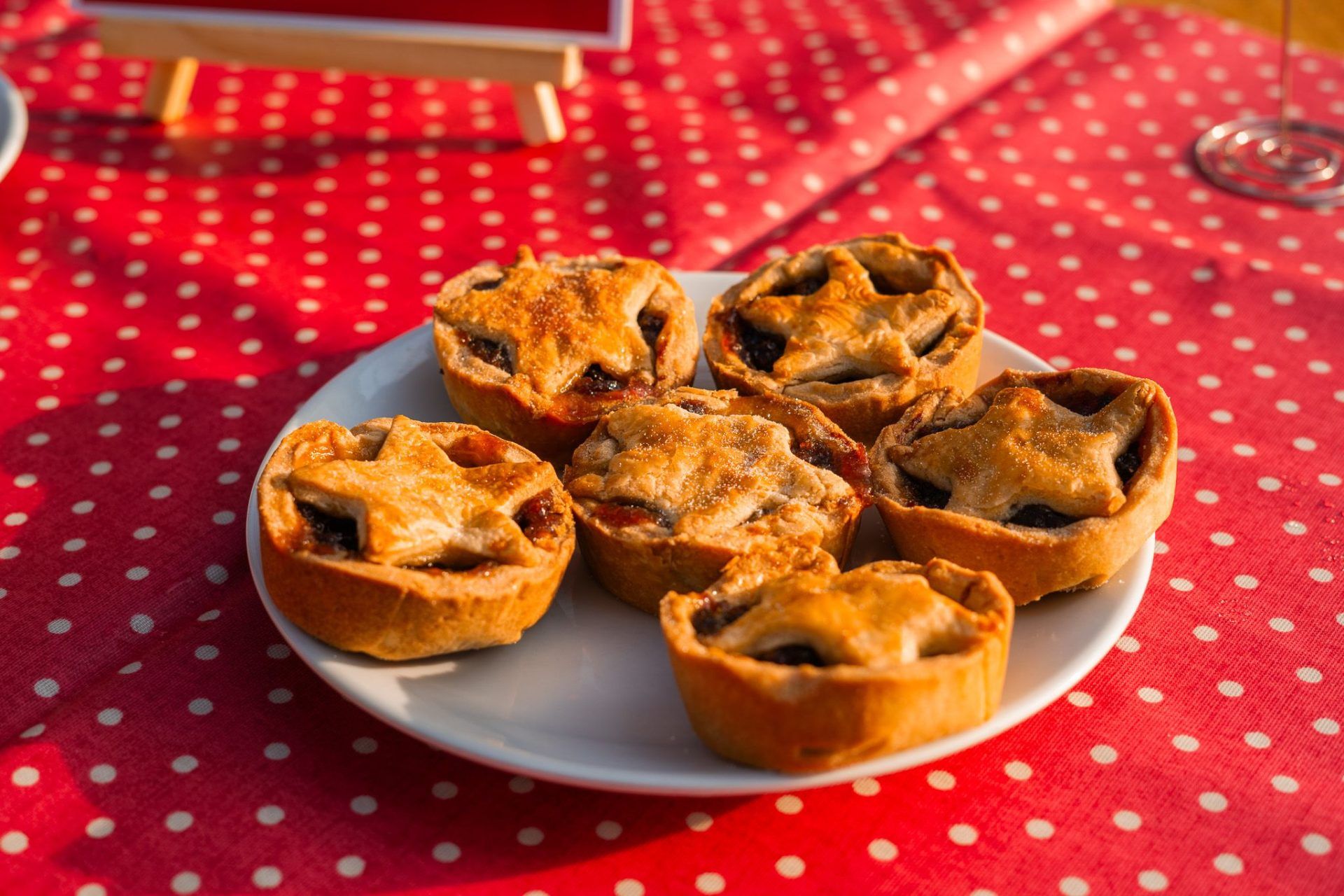 Sun-dappled mince pies on a red spotty tablecloth
