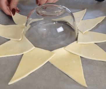 Clear upside down bowl with pastry triangles arranged around the outside in a star shape