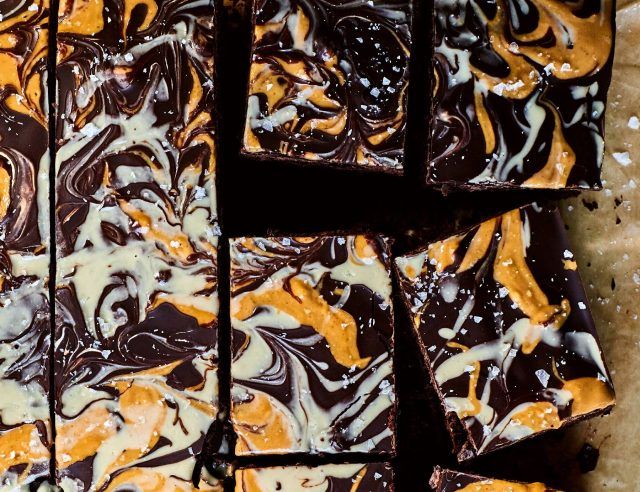 Chocolate peanut tahini brownies arranged on baking powder - the tahini and peanut butter are swirled into the top.