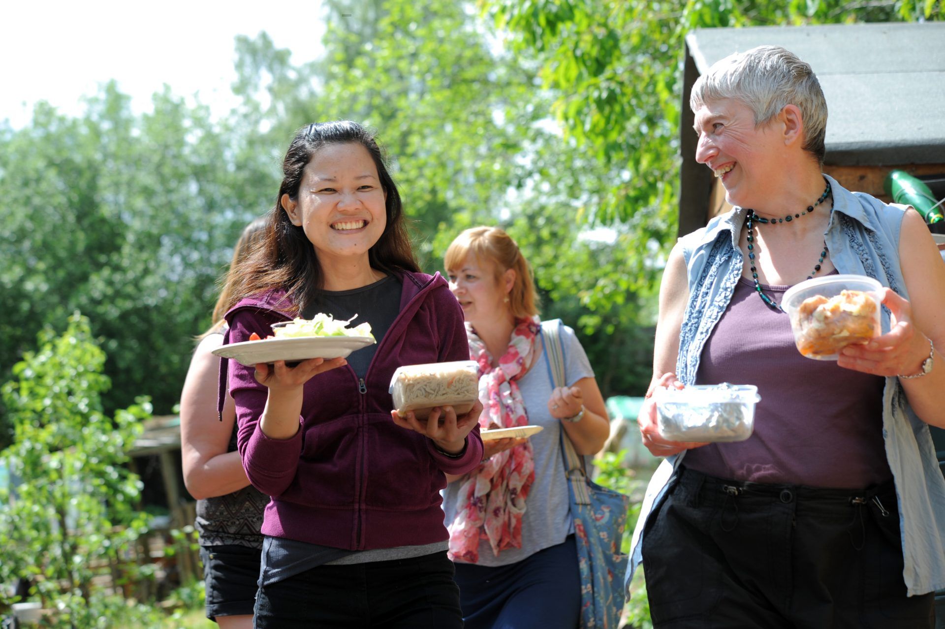 Two women smiling and holding food at a Big Lunch