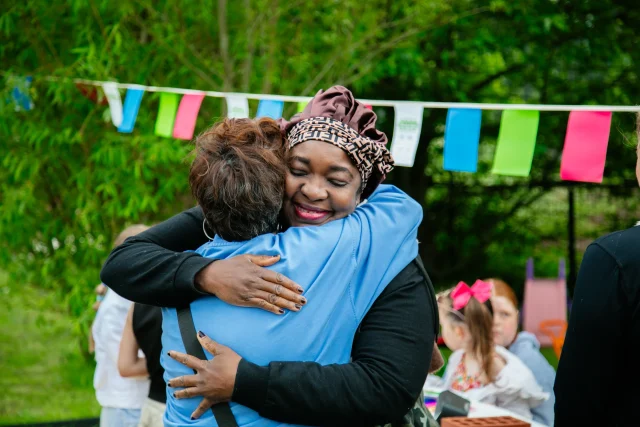 Two women sharing a moment of connection with a warm hug at a community The Big Lunch
