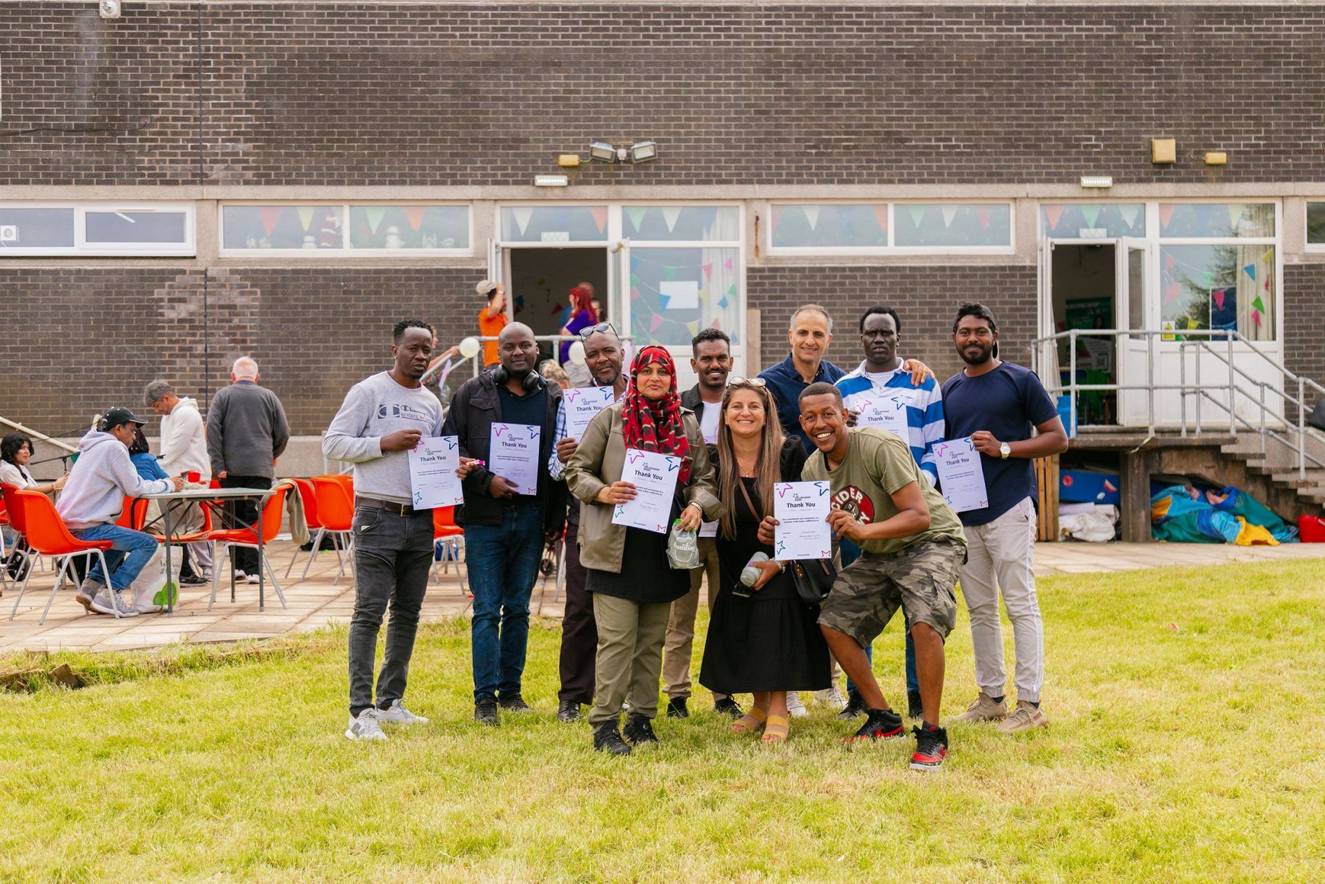 A group of volunteers at the Love Barrow Libraries Big Lunch are gathered for a photo to show the certificates they have been presented. They are happy and smiling.