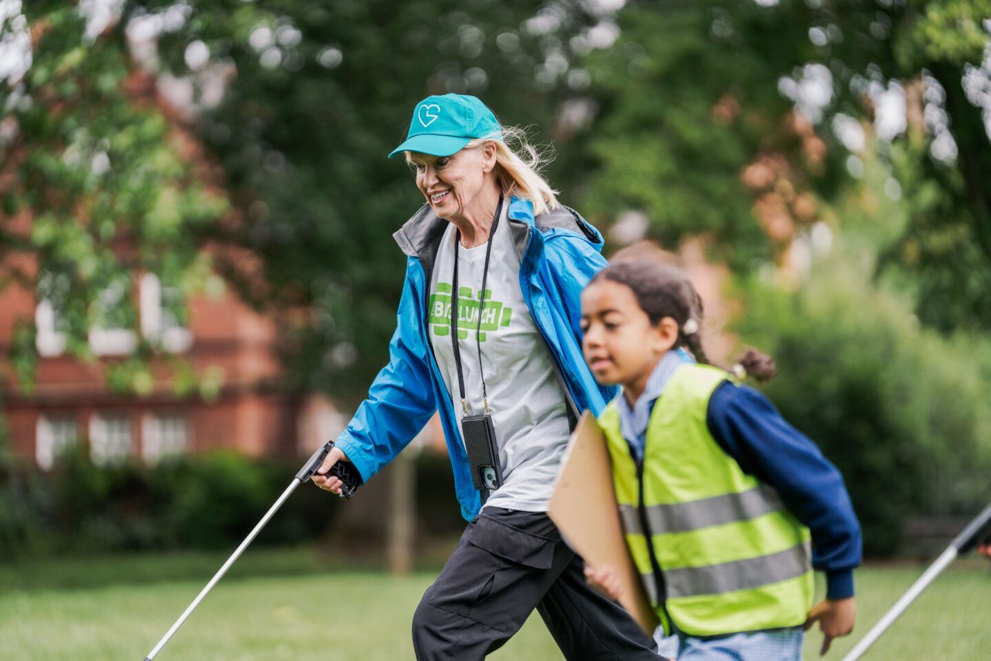 Anneka Rice walks with a litter picker next to a child - they both look like they're having fun!